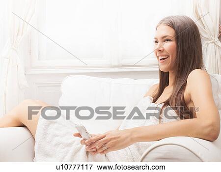 Stock Photo - Woman wrapped in towel using cell phone. Fotosearch