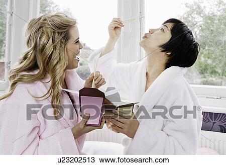 Stock Image - Women in bathrobes eating Chinese food. Fotosearch