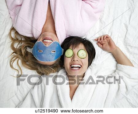 Stock Image - Women in bathrobes wearing eye masks. Fotosearch