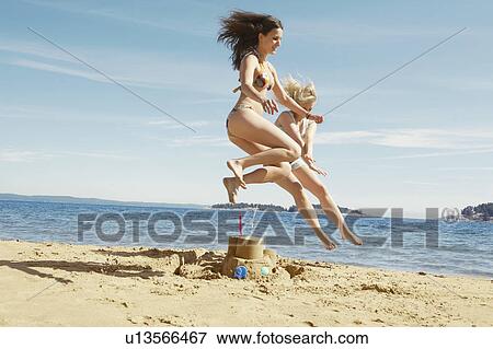 Women jumping over sandcastle View Large Photo Image Stock Photo - Women jumping over sandcastle. Fotosearch