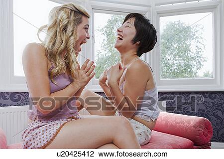 Stock Image - Women laughing in bedroom. Fotosearch