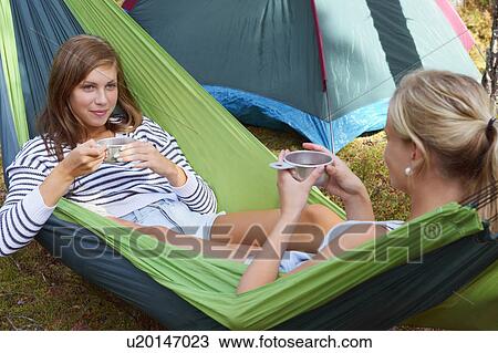 Stock Image - Women relaxing in hammock at campsite. Fotosearch