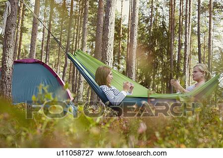 Women relaxing in hammock at campsite View Large Photo Image Stock Photo - Women relaxing in hammock at campsite. Fotosearch