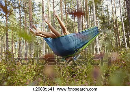 Stock Image - Women relaxing in hammock in forest. Fotosearch