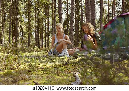 Women sitting at campsite in forest View Large Photo Image Stock Photograph - Women sitting at campsite in forest. Fotosearch