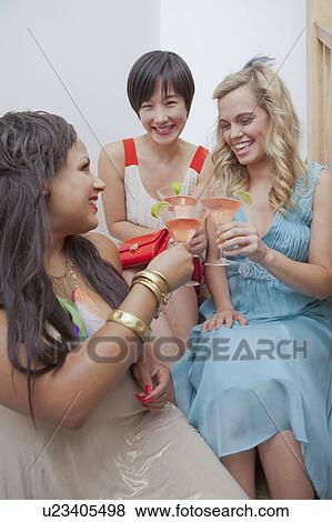 Stock Photo - Women toasting each other with martinis. Fotosearch