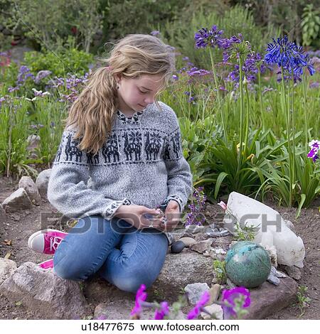 Stock Photography - A Girls Sits On Stones By A Flower Garden At The Willka T'ika Guesthouse; Peru. Fotosearch