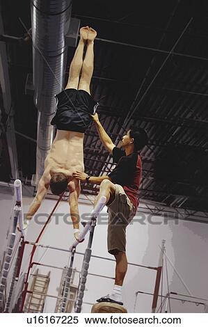 Stock Photography - Coast Assisting An Athlete With Parallel Bars. Fotosearch