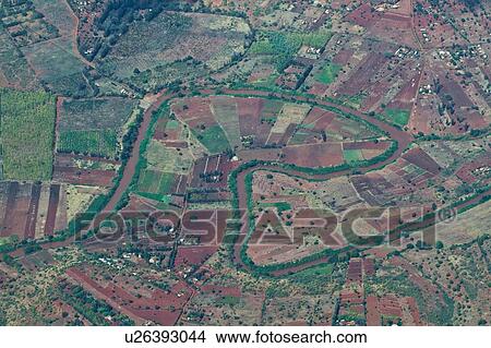 Picture - Aerial view of cultivated farmland, creating patchwork of rectangles and patterns, serpentine river winding through, Kenya, East Africa. Fotosearch