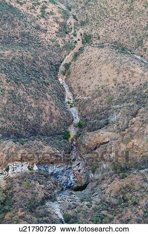 Stock Photo - Aerial view of dry rocky river bed and surrounding slopes in Lewa Downs plain, Kenya, East Africa. Fotosearch