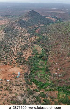 Stock Photo - Aerial view of green valley in Lewa Downs plain, with sandy soil, bushes and scattered houses, Lewa Downs, Kenya, East Africa. Fotosearch