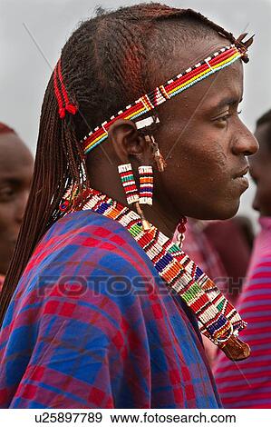 Close up side view of young Masai warrior (moran), with long braided hair, wearing traditional red and blue shuka and beaded jewellery, Amboseli, Kenya, East Africa View Large Photo Image Stock Photo - Close up side view of young Masai warrior (moran), with long braided hair, wearing traditional red and blue shuka and beaded jewellery, Amboseli, Kenya, East Africa. Fotosearch