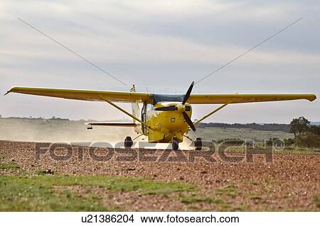 Front view of yellow Cessna plane at speed taking off on dirt runway, Masai Mara, Kenya, East Africa View Large Photo Image Picture - Front view of yellow Cessna plane at speed taking off on dirt runway, Masai Mara, Kenya, East Africa. Fotosearch