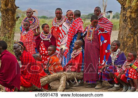 Group of beautiful Masai women, all wearing colourful clothing and much beaded jewellery, sit on fallen tree trunk, waiting after face paint application, for celebrations to begin, Amboseli, Kenya, East Africa View Large Photo Image Stock Photo - Group of beautiful Masai women, all wearing colourful clothing and much beaded jewellery, sit on fallen tree trunk, waiting after face paint application, for celebrations to begin, Amboseli, Kenya, East Africa. Fotosearch