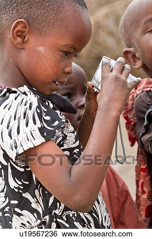 Stock Photograph - Masai child, close up side view, gazing at her photo on camera LCD, Amboseli, Kenya, East Africa. Fotosearch