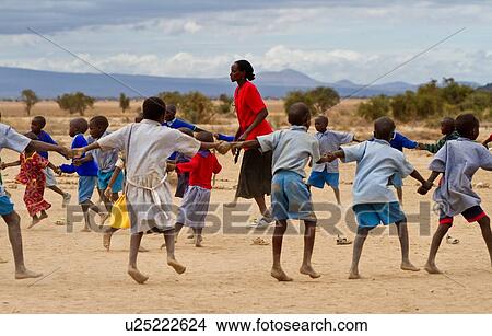 Masai school out on the plains: a group of children, mostly dressed in blue sweaters, and blue check clothing dance in a circle around their teacher, dressed in red, Amboseli, Kenya, East Africa View Large Photo Image Picture - Masai school out on the plains: a group of children, mostly dressed in blue sweaters, and blue check clothing dance in a circle around their teacher, dressed in red, Amboseli, Kenya, East Africa. Fotosearch