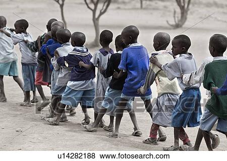 Stock Photo - Masai school outdoors: desaturated image of children dressed in blue sweaters and blue check outfits, forming a diagonal conga line, Amboseli, Kenya, East Africa. Fotosearch