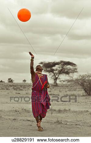 Masai warrior, dressed in traditional red and blue shuka playing with orange balloon: desaturated image, Amboseli, Kenya, East Africa View Large Photo Image Stock Image - Masai warrior, dressed in traditional red and blue shuka playing with orange balloon: desaturated image, Amboseli, Kenya, East Africa. Fotosearch