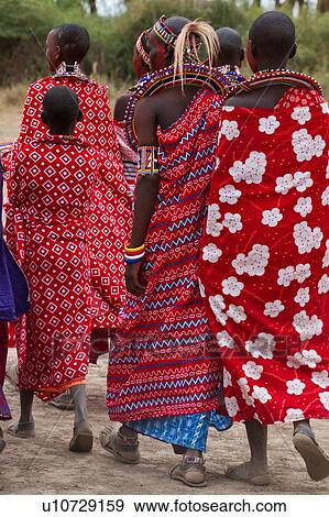 Stock Photo - Masai women: close up of group of beautifully dressed women walking away, all wearing red and white cotton wraps, and much beaded jewellery, with faces painted for celebrations, Amboseli, Kenya, East Africa. Fotosearch