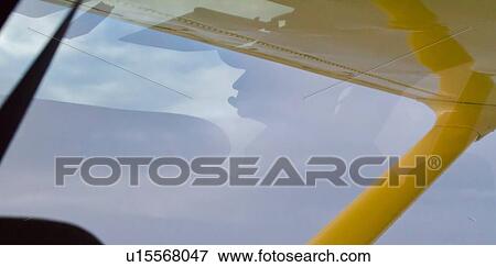 Stock Photo - Silhouette view of pilot's head reflected in windscreen while flying yellow Cessna plane, Kenya, East Africa. Fotosearch