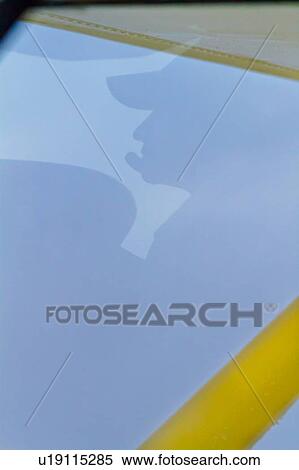 Stock Photography - Silhouette view of pilot's head reflected in windscreen while flying yellow Cessna plane, Kenya, East Africa. Fotosearch