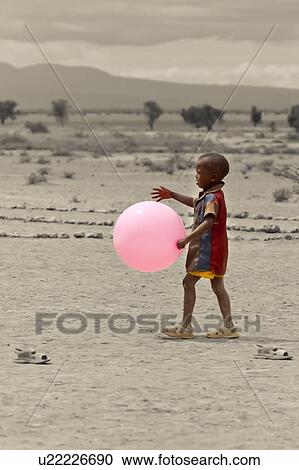 Small Masai boy, seen from side, walking and carrying very large pink balloon, plains beyond, desaturated background, Amboseli, Kenya, East Africa View Large Photo Image Stock Image - Small Masai boy, seen from side, walking and carrying very large pink balloon, plains beyond, desaturated background, Amboseli, Kenya, East Africa. Fotosearch