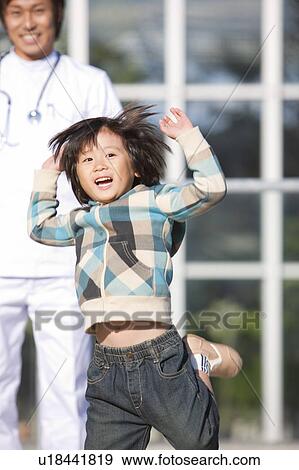 Stock Photo - Boy Jumping, Doctor in Background. Fotosearch