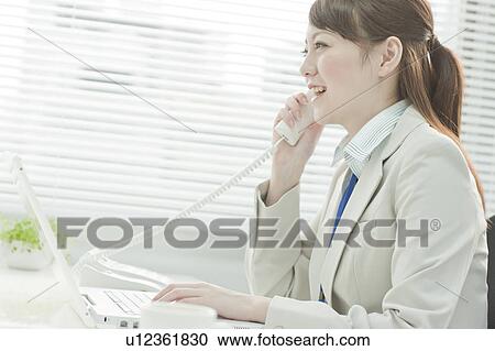 Stock Image - Businessman Woman Using Laptop and Talking on Phone. Fotosearch