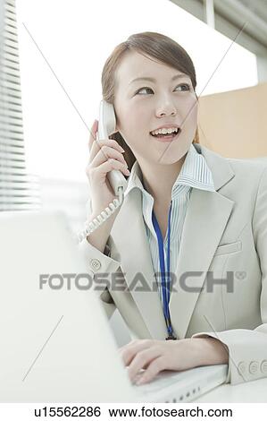 Stock Photograph - Businessman Woman Using Laptop and Talking on Phone. Fotosearch