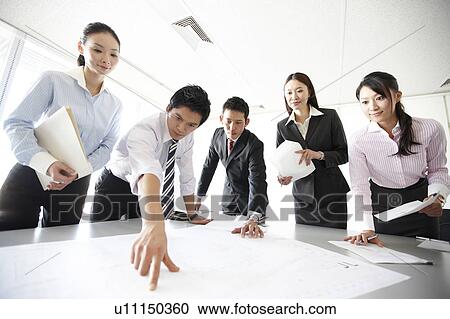 Stock Image - Businesspeople Looking at Documents in Meeting. Fotosearch