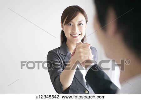Stock Image - Businesswoman and Businessman Shaking Hands. Fotosearch