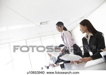 Stock Image - Businesswoman Talking Standing Up in Meeting. Fotosearch