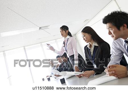Stock Photo - Businesswoman Talking Standing Up in Meeting. Fotosearch