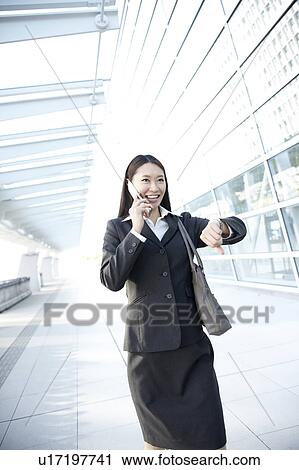 Stock Image - Businesswoman Walking and Talking On Phone. Fotosearch