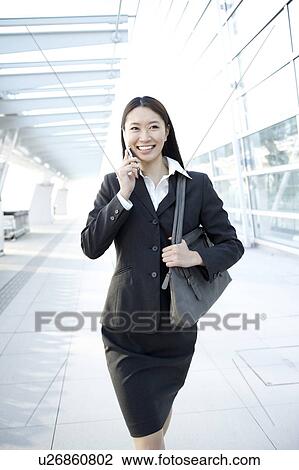 Stock Image - Businesswoman Walking and Talking On Phone. Fotosearch