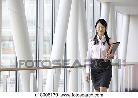 Stock Image - Businesswoman Walking in Corridor. Fotosearch