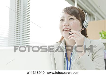 Stock Image - Businesswoman with Laptop Using Headset. Fotosearch