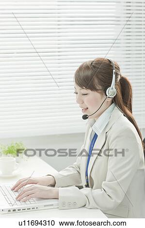 Stock Image - Businesswoman with Laptop Using Headset. Fotosearch