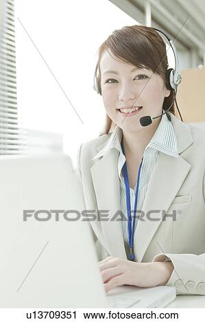 Stock Image - Businesswoman with Laptop Using Headset. Fotosearch