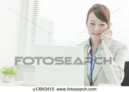 Stock Image - Businesswoman with Laptop Using Headset. Fotosearch