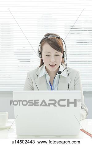 Stock Image - Businesswoman with Laptop Using Headset. Fotosearch