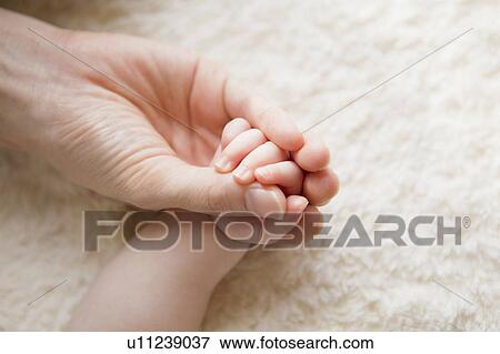 Stock Photo - Close-up of mother holding baby's hand. Fotosearch