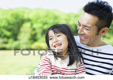 Stock Image - Daughter sitting on father's lap. Fotosearch