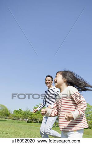 Stock Image - Father and daughter running in park. Fotosearch