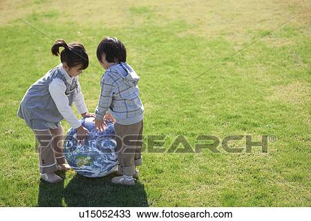 Stock Image - Girl and Boy with Globe Beach Ball. Fotosearch