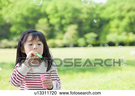 Stock Image - Girl blowing bubbles. Fotosearch