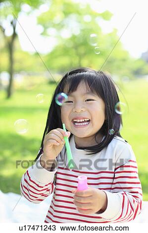 Stock Image - Girl blowing bubbles. Fotosearch