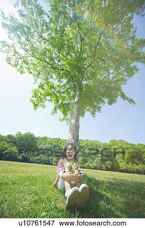 Girl holding a potted plant leaning on a tree View Large Photo Image Stock Photo - Girl holding a potted plant leaning on a tree. Fotosearch