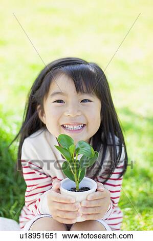 Girl holding a potted plant View Large Photo Image Stock Image - Girl holding a potted plant. Fotosearch