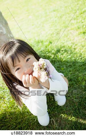 Stock Photo - Girl holding wildflowers and hand on chin. Fotosearch